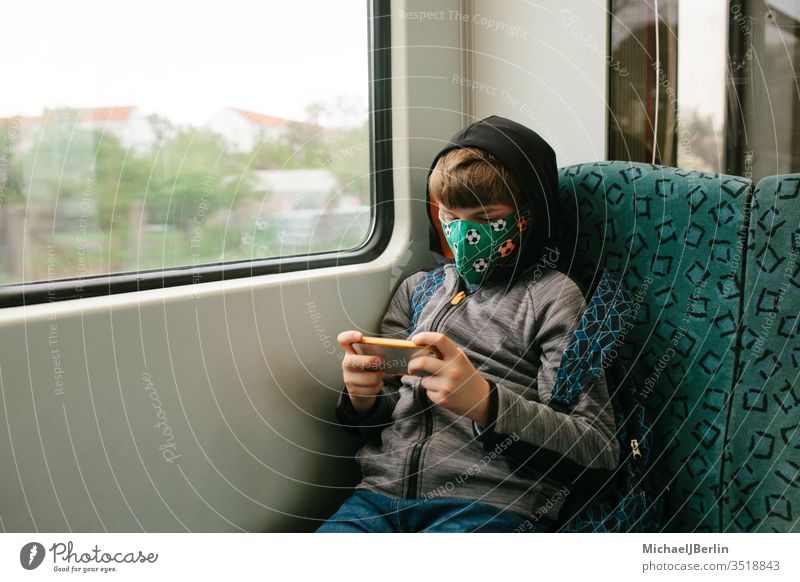 Junge mit Gesichtsmaske sitzt im öffentlichen Verkehr junge kind schutz Mund-Nasen-Maske mns Community-Maske S-Bahn Öffentlicher Personennahverkehr