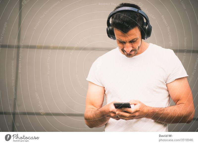 Mann hört über sein Handy mit Bluetooth-Kopfhörer Musik Bluetoothkopfhörer Verbindung Verbindungstechnik verbunden Elektronik Technik & Technologie Fortschritt