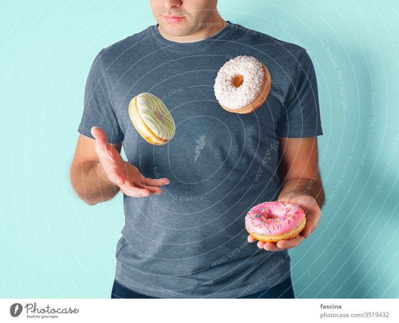 Jongleur jongliert mit Donuts auf blauem Hintergrund Mann Doughnuts Versand Gesundheit ungesund Diät Zucker Jonglieren Konzept Spiel spielen Café Streusel