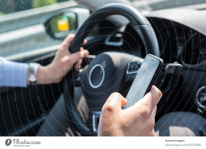 Geschäftsmann schreibt während der Fahrt eine SMS auf seinem Mobiltelefon. Telefon Mobile PKW Fahrer Technik & Technologie Business Person Automobil Texten