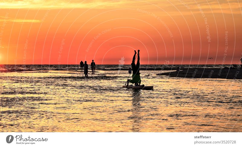 Umgedrehter Handstand auf einem Paddelbrett bei Sonnenuntergang Kopfstand Abenddämmerung Meer Yoga Laguna Beach Surfer Kalifornien Küste Küstenlinie