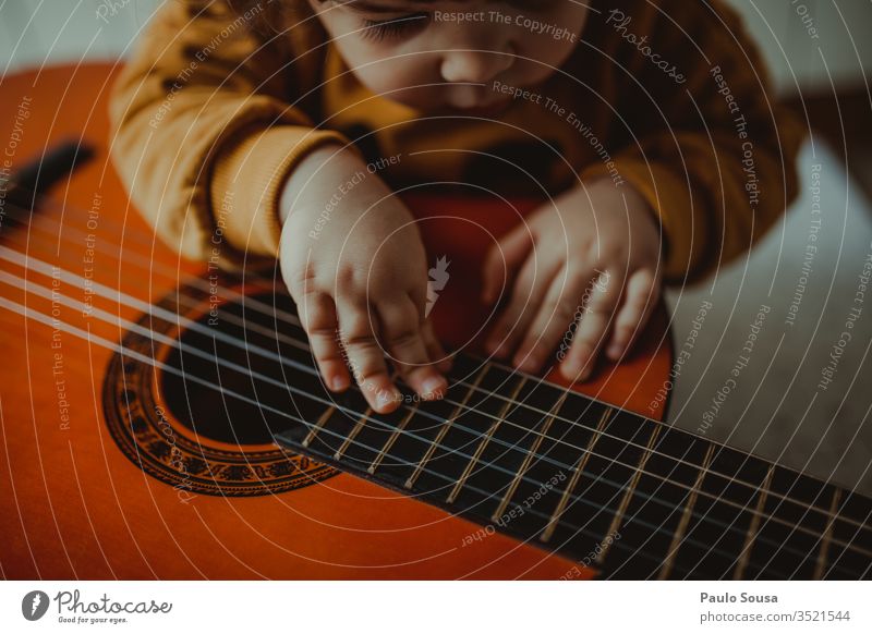 Gitarre spielendes Kind Spielen Fröhlichkeit Kaukasier im Innenbereich Neugier unschuldig Mädchen heimwärts Blick gemütlich Freude Lifestyle niedlich Kindheit