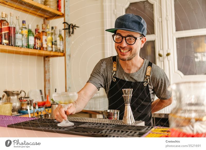 Kellner zeigt ein eiskaltes Glas mit einem an der Bar einer modernen Bar zubereiteten Cocktail zeigen dienen Alkohol Lächeln transferieren liquide Brille Minze