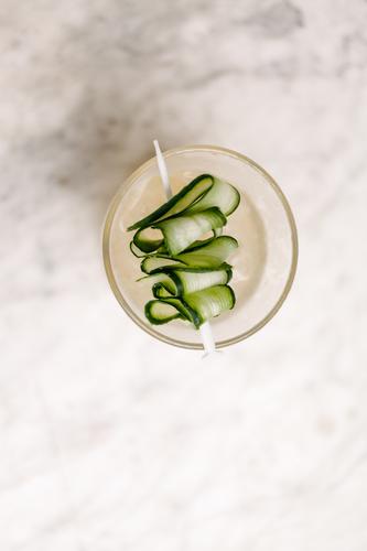 Teller mit einem Gurkenspieß auf weißem Hintergrund vertikal Antenne Gemüse Salatgurke Spieß Genuss Lebensmittel Lebensstile reich verdrehen Cocktail filigran