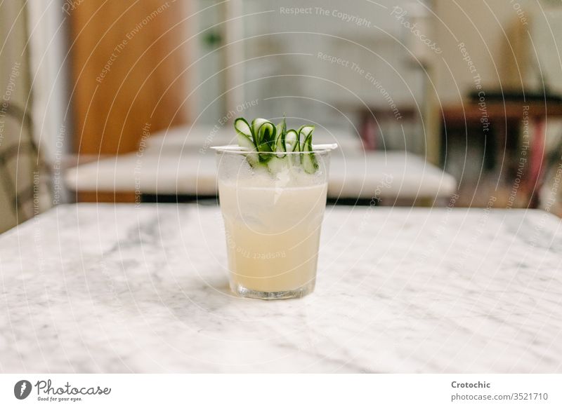 Weißlikör-Cocktail mit einigen Gurkenstücken zum Dekorieren, serviert auf einem Marmortisch in einer Bar Salatgurke weiß Murmel Tisch Stuhl gemischt Erfrischung