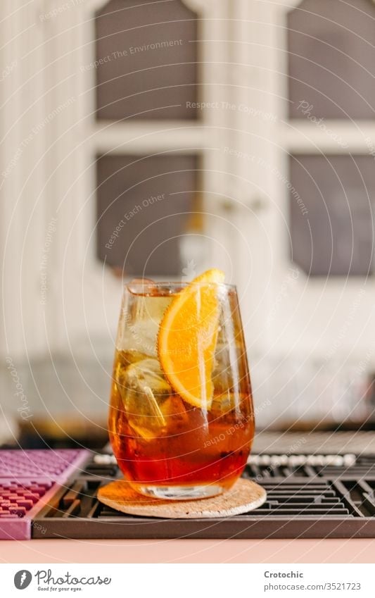 Vertikales Foto eines Kristallglases mit einem eisgekühlten Cocktail mit einem Stück Orange zur Dekoration in einer Bar vertikal trinken Alkohol cool Eis