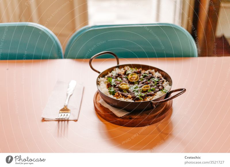 Pfanne mit Reis und Bohnen, dekoriert mit gehackten grünen Chilischoten, serviert auf einem Holztisch Tisch hölzern Gabel Serviette bereit heiß
