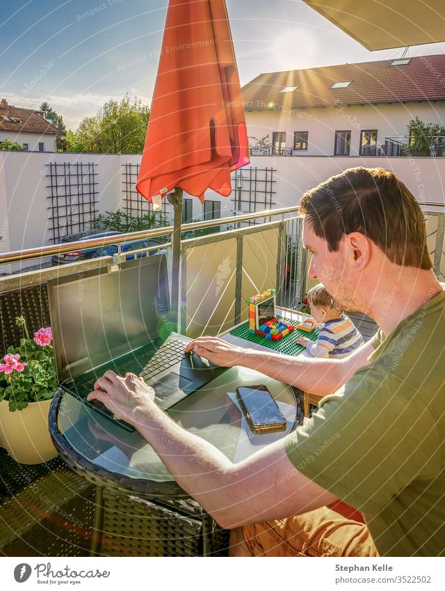 Das Innenministerium, Vater und Sohn arbeiten zusammen mit ihren Laptops zu Hause auf dem Balkon, während die Sonne scheint. Neuer Lebensstil durch Korona, Covid-19-Pandemie.