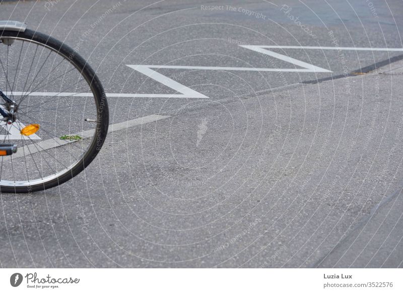 Fahrrad, abgestellt an einer Sperrfläche: perfekte Geometrie aus Speichen, rund, zickzack und sogar ein wenig grün. Rad Speichenrad Straße geometrisch Zickzack