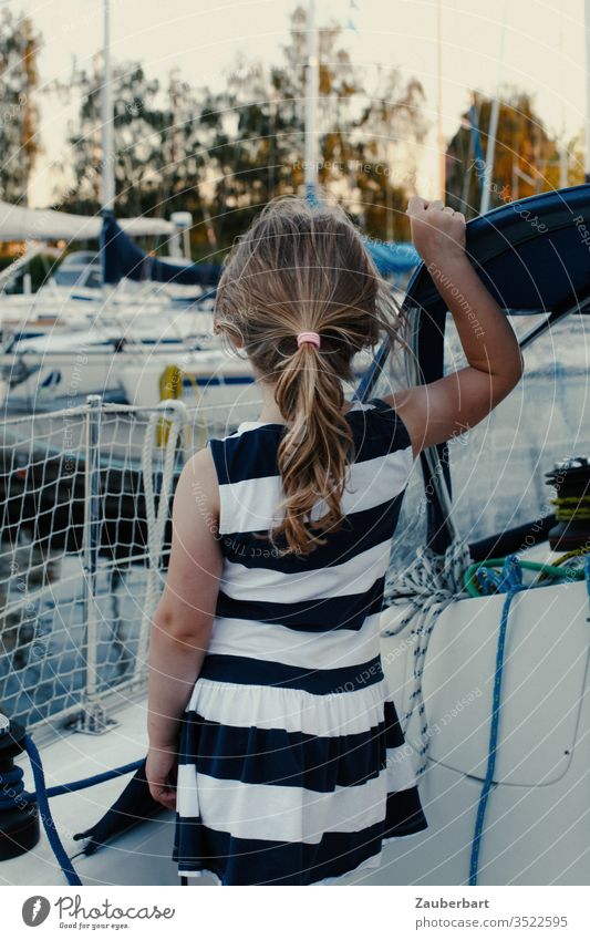Mädchen im gestreiften Kleid auf einem Segelboot schaut in den Hafen Kind Pferdeschwanz Streifen Reling Segeln Sommer stehen träumen Kindheit Yacht Wasser Jacht