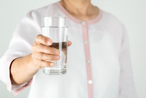 Trinkwasser in der Hand der älteren Frau, Konzept des Umweltschutzes, gesundes Trinken. Erwachsener gealtert aqua attraktiv Hintergrund schön Getränk Flasche