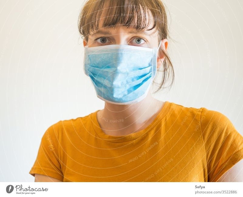 Junge Frau mit schützender Gesichtsmaske Mundschutz COVID19 Coronavirus Quarantäne zu Hause bleiben allein Schutz Isolation Seuche Virus Grippe Mädchen