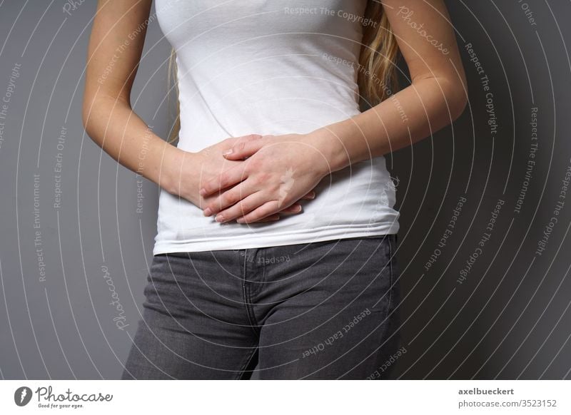 nicht erkennbare junge Frau, die ihren Bauch mit beiden Händen hält - Konzept für Bauchschmerzen, Reizdarmsyndrom, Bauchschmerzen, schmerzhafte Perioden oder Menstruationskrämpfe