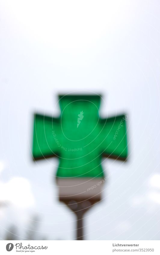 DAS GRÜNE KREUZ. Apothekersymbol unscharf vor Himmel meer grün Signal Grünfläche durchlicht transparent durchscheinend Wolken Sommer Hilfe international Zeichen