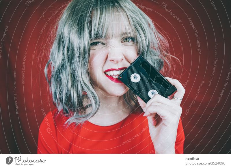 Künstlerisches Porträt mit einem Modell, das sein Gesicht mit einem Retro-Videoband bedeckt retro altehrwürdig Kassette Klebeband rot Frau sexy hübsch Musik