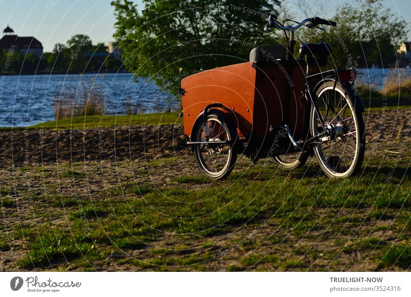 Sehr Trend bewusst präsentiert sich das neue Lastenrad auf einer Wiese mit Sand am Havel-Strand in der Abendsonne Fahrrad Dreirad Rikscha Umwelt