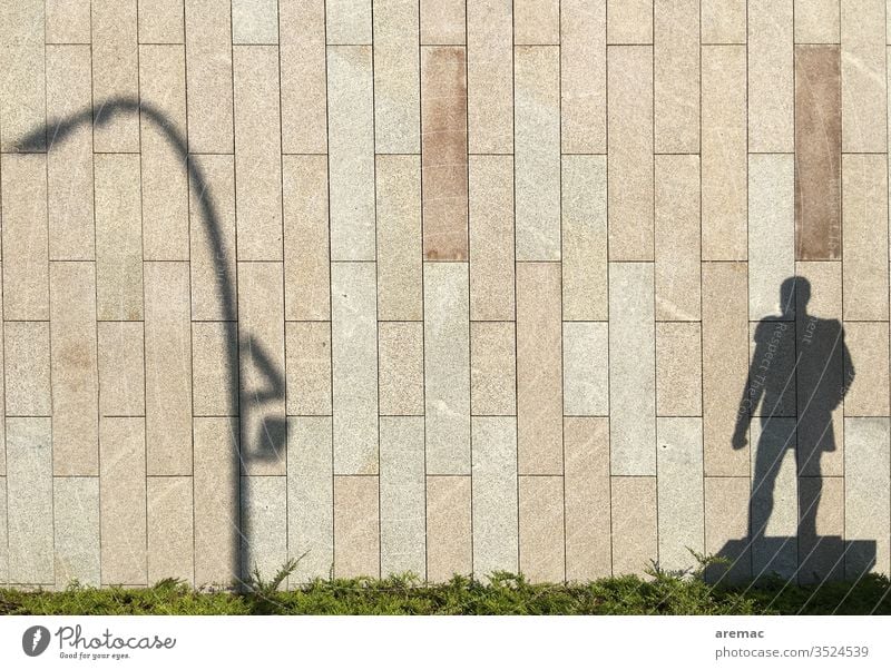 Schatten eines Denkmals und einer Laterne an der Wand Fassade Schattenspiel Licht Mann Mauer Außenaufnahme Tag Menschenleer Farbfoto Architektur Haus Stadt