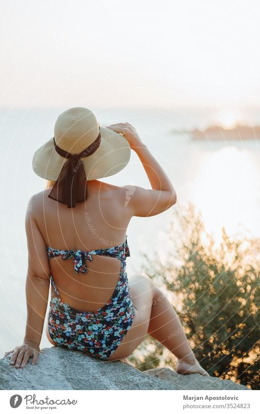 Junge Frau genießt Sonnenuntergang am Meer Abenteuer schön Schönheit sorgenfrei Klippe Küste Küstenstreifen Küstenlinie genießend Abend Freiheit Mädchen Hut