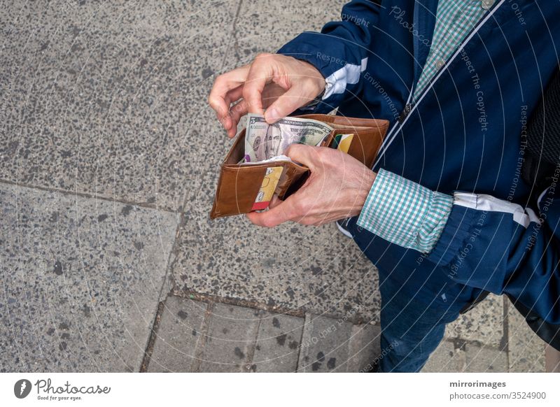 Mann, der seine Brieftasche öffnet, um etwas Bargeld in amerikanischer Währung auszugeben Wirtschaft und Finanzen Barzahlung Wirtschaft und Zahlungen