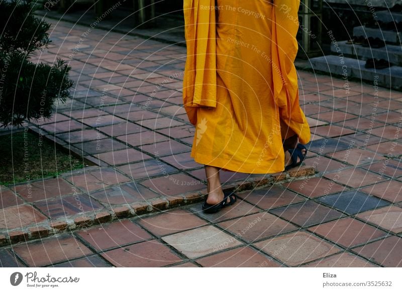 Ein buddhistischer Mönch in traditionellem orangefarbenen Gewand Buddhismus Religion & Glaube Asien Kutte Mönchskutte Ti-cîvara gehen Füße nackt Sandalen