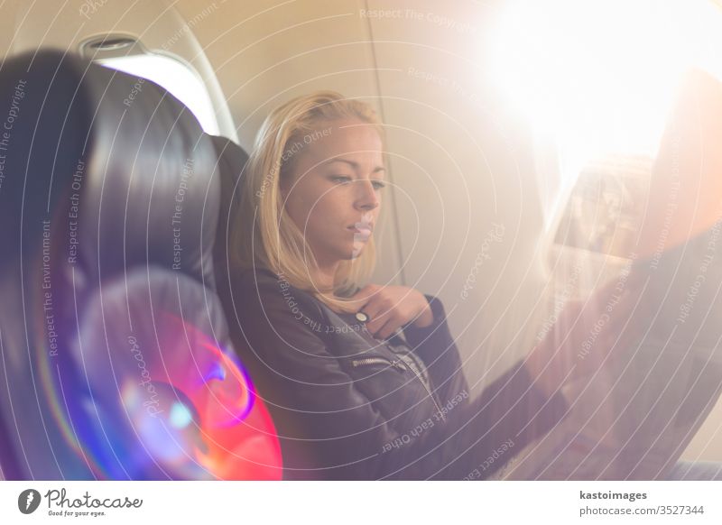 Frau liest Zeitung im Flugzeug. Passagier reisen Verkehr Ausflug lesen Sitz Ebene jung Air Transport Mädchen im Inneren Reise Kaukasier Kabine Fenster Fluggerät