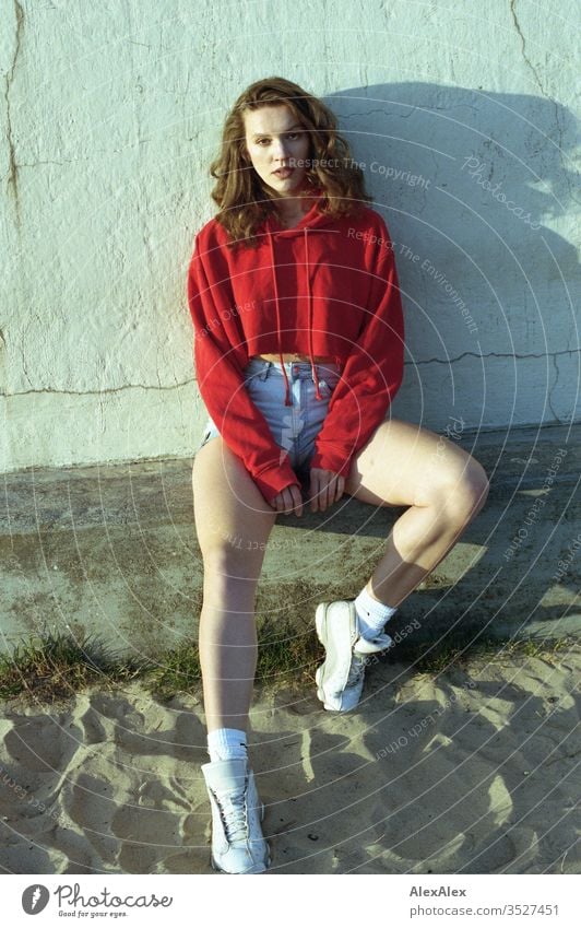analoges Portrait einer jungen Frau mit roten Hoodie und Hotpants Mädchen schön groß sportlich schlank fit brünett Hot Pants Locken langes Haar Sneaker Beine