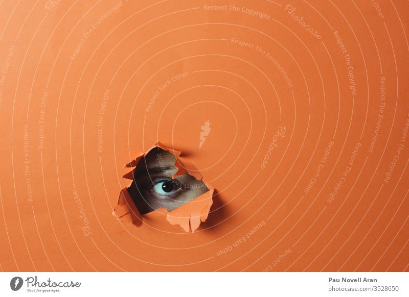 Das Auge schaut durch das Loch. Abstrakter Hintergrund Frau Golfloch orange abstrakt vereinzelt Aussehen Papier Textfreiraum hell Farbe farbenfroh natürlich