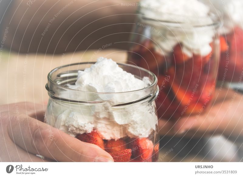 Einweckgläser mit geschnittenen Erdbeeren und Sahnehäubchen Einmachglas Einweckglas Nachtisch Nachspeise essen naschen ernähren Ernährung Hand Hände festhalten