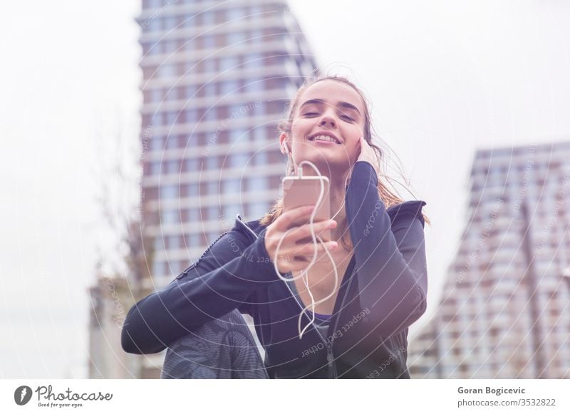 Lächelnde junge Frau mit Smartphone und Kopfhörern beim Musikhören Lifestyle Glück Mädchen im Freien modern Person Sommer Teenager außerhalb genießend Kaukasier