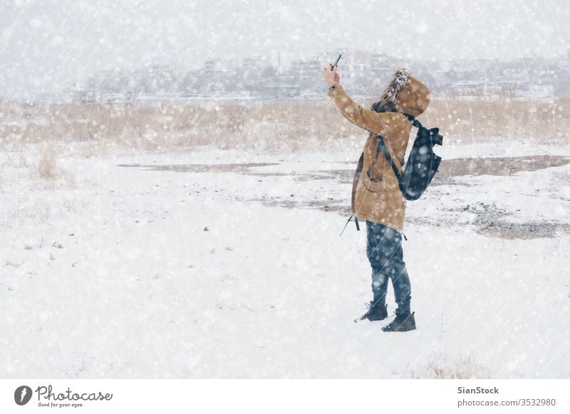 Frau fotografiert in verschneiter Landschaft Schnee Winter laufen Telefon Selfie nimmt Foto Smartphone mpbile kalt im Freien Schritt weiß Spaziergang Natur Mode