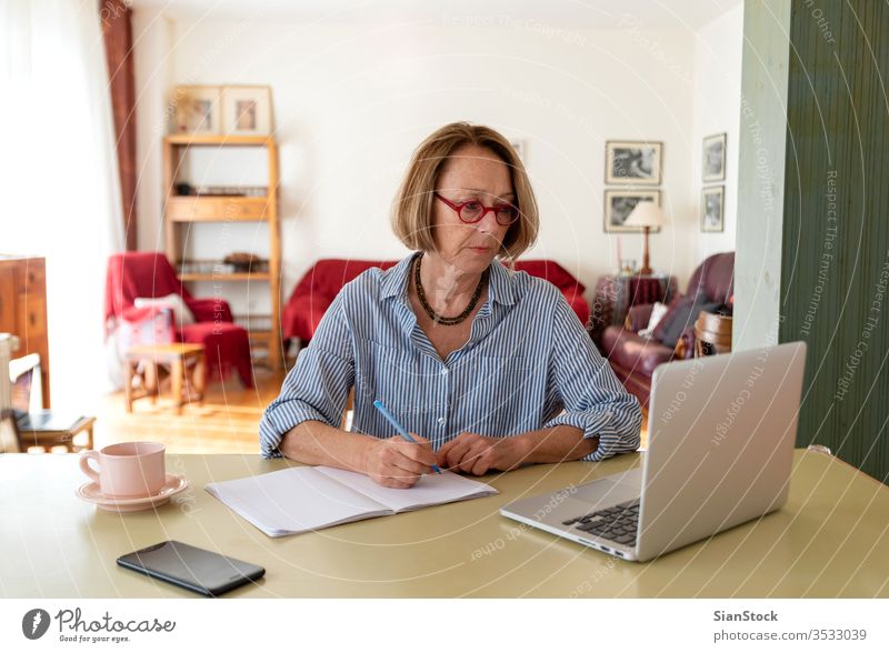 Senioren mittleren Alters, die zu Hause am Computer arbeiten Frau Laptop reif Menschen eine Person Lifestyle Schreibtisch benutzend trinken Brille attraktiv