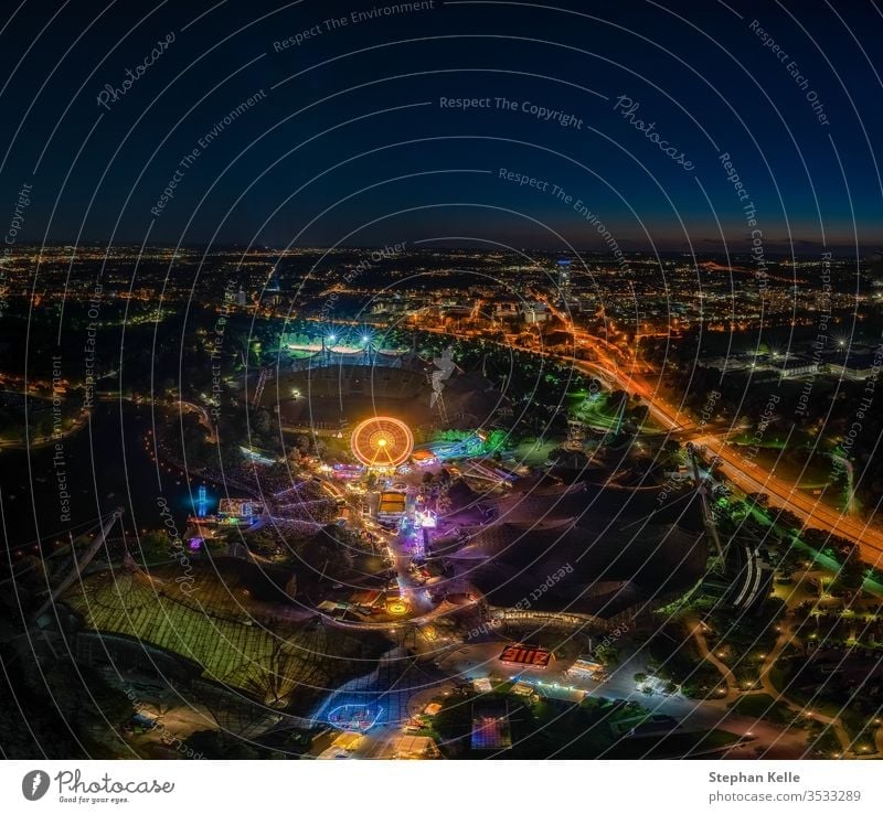ein eindrucksvolles Nachtansichtsfoto über München vom Olympiaturm beim nächtlichen ImPark-Fest mit beleuchtetem Riesenrad. Spaß Verkehr mit langer Exposition