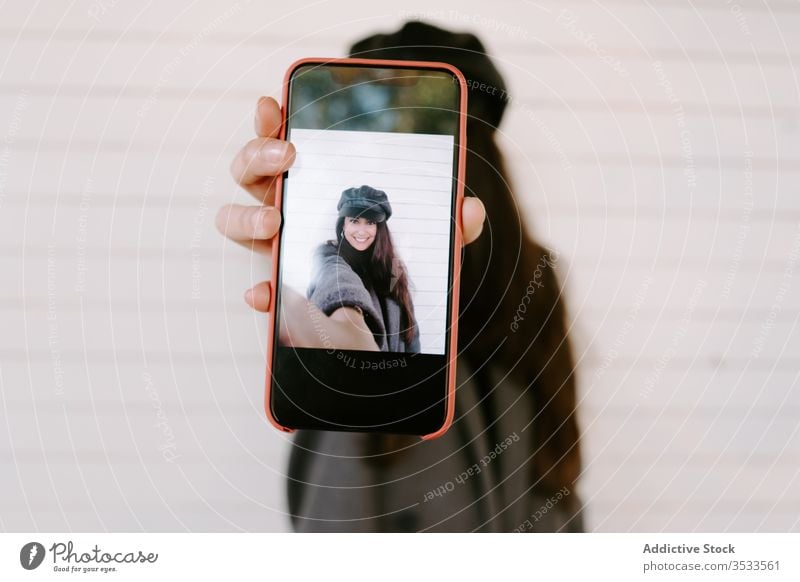 Junge Frau zeigt Smartphone mit Selfie zeigen Wand Straße Großstadt urban modern jung Gebäude Foto Telefon Mobile soziale Netzwerke teilen manifestieren
