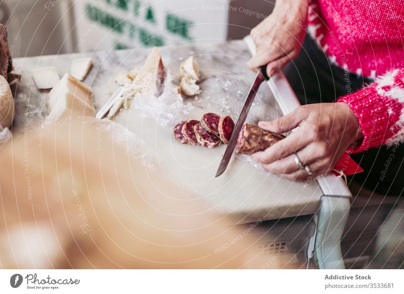 Ernteverkäufer schneidet Wurst auf der Theke Verkäufer geschnitten Wurstwaren Werkstatt Abfertigungsschalter Lebensmittel lokal Küche Arbeit Messer Käse