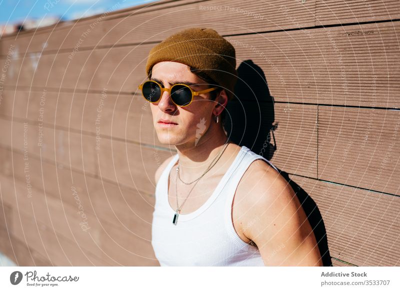 Stilvoller Mann an der Wand stehend Straße modern urban jung Großstadt Sonnenbrille Tanktop männlich trendy Model Hipster sonnig Gebäude Konstruktion cool