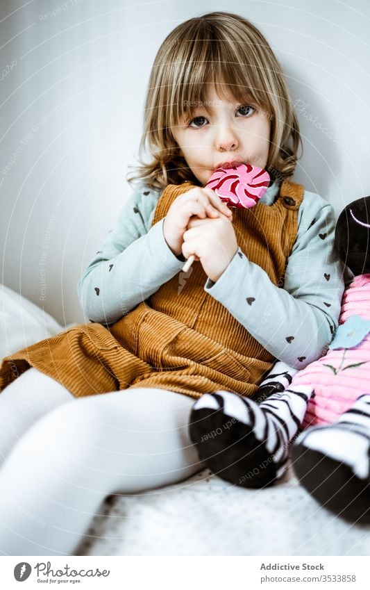 Kleines Mädchen isst Süßigkeiten im Bett Lollipop saugen heimwärts Spielzeug sitzen ruhen niedlich wenig Schlafzimmer Kind Plüsch süß Kindheit weich gemütlich