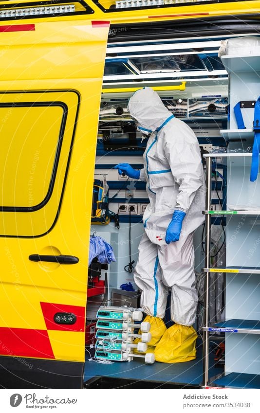 Arzt im Schutzanzug im Rettungswagen stehend PKW Tür Krankenwagen Gerät geduldig Virus Infektion untersuchen Uniform inspizieren Krankenhaus Dienst Fahrzeug