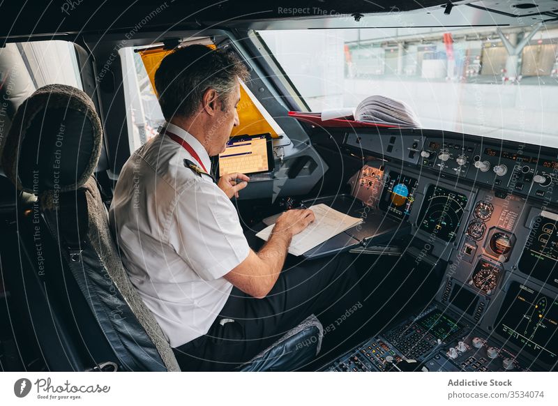Kapitän überprüft Flugdokument im Flugzeug-Cockpit Pilot Schriftstück lesen vorbereiten prüfen Mann Flieger männlich modern Fluggerät Ebene Verkehr Luftverkehr