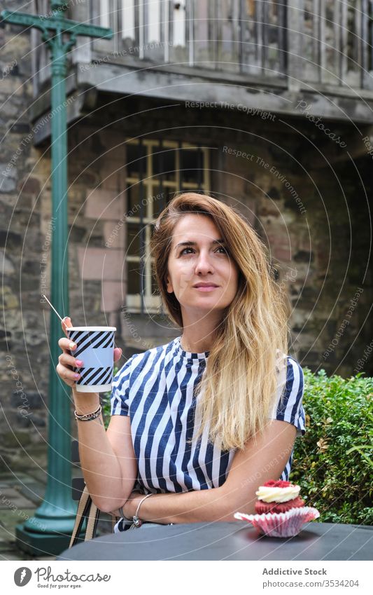 Nachdenkliche Frau mit Tasse Kaffee und Muffin im Cafe Getränk Cupcake Café Quadrat alt Stadt Inhalt träumen nachdenklich verträumt Lifestyle Freizeit ruhen