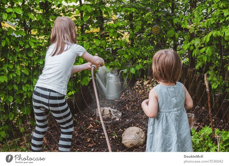 Ein Mädchen gießt den Garten, das andere guckt zu Kinder Farbfoto gießen Zusammenhalt Zuneigung Freizeit & Hobby Gartenarbeit Hecke Spaß haben Engagement
