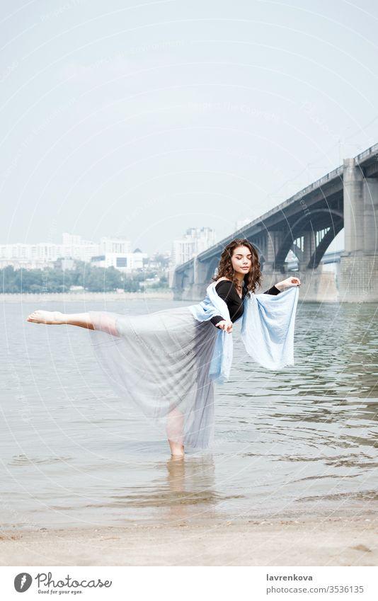 Junge erwachsene weiße Frau am Strand beim Arabesken im Wasser, selektiver Fokus Tänzer Bewegung schön Ästhetik Lifestyle Kleid Natur MEER Balletttänzer Ufer