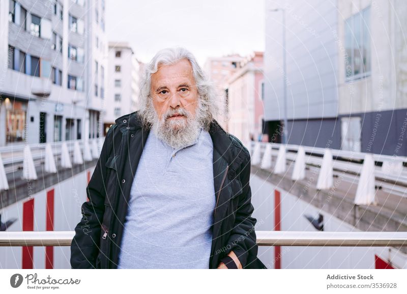 Älterer männlicher Reisender steht auf einer Brücke mit dahinter liegenden städtischen Straßengebäuden Senior Mann urban Gebäude reisen erkunden ernst Tourismus