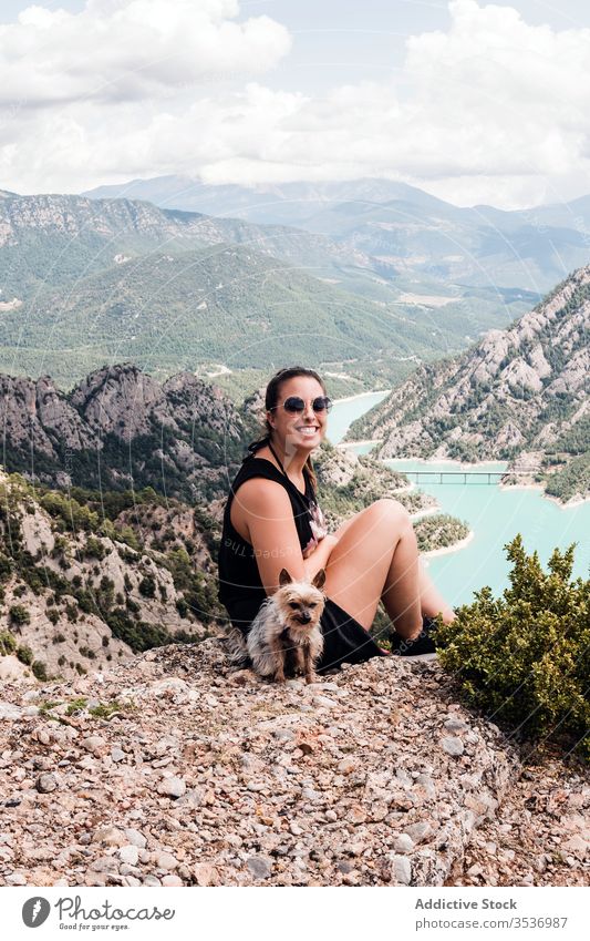 Anonyme Touristin mit Hund sitzt auf einem Hügel und genießt die Landschaft Frau Sommer Ausflug Natur Urlaub ruhen Haustier Sonnenbrille schwarz malerisch Reise