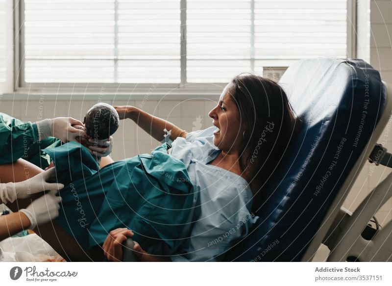 Frau, die im Krankenhaus entbindet Geburt Baby Schmerz Grunzen packen Stuhl Arzt modern Handgriff medizinisch Pflege geduldig Gesundheitswesen Medizin