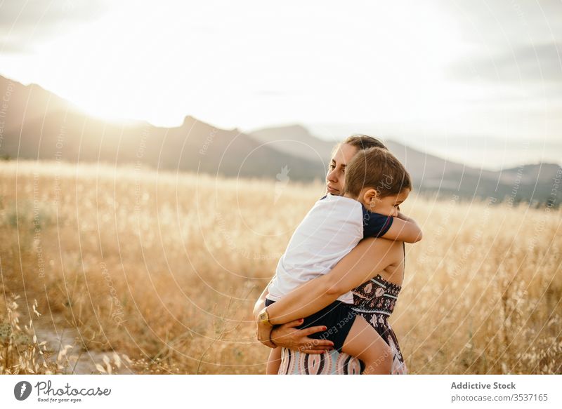 Mutter und Sohn ruhen auf dem Feld Sonnenuntergang Umarmung führen Berge u. Gebirge Liebe Gras Abend Frau Junge Erwachsener Wiese Himmel Natur Zusammensein
