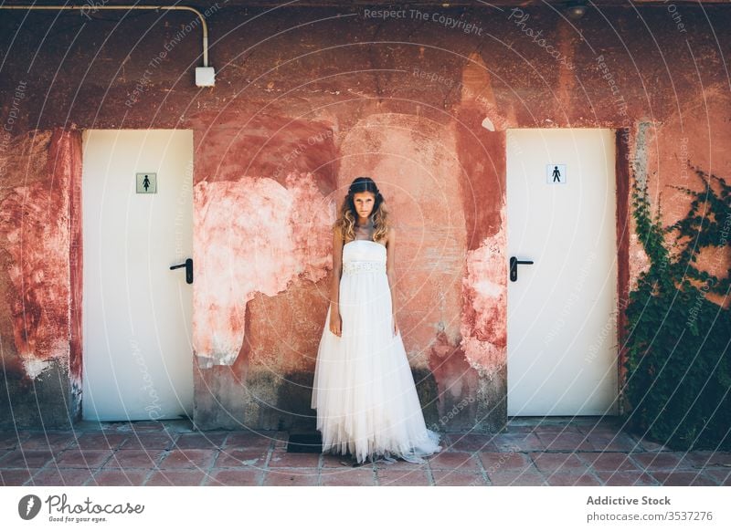 Sinnliche junge Braut in weißem Kleid steht an schäbiger Wand Frau rot Toilette Hochzeit elegant romantisch charmant Stil schön Heirat attraktiv Veranstaltung