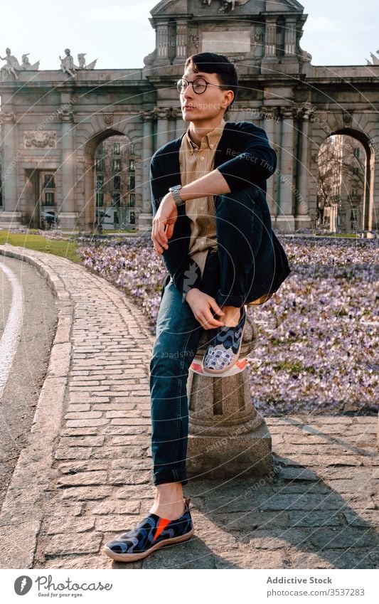 Stilvoller junger asiatischer Mann posiert im Stadtpark trendy Mode Architektur selbstbewusst Außenseite antik Sicht Model Brille historisch Großstadt Gebäude