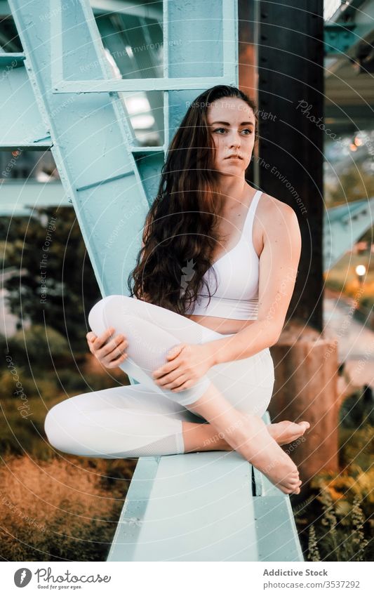 Nachdenkliche Frau sitzt auf einem Metallbalken der Brücke Stadtbild nachdenklich Sportbekleidung genießen verträumt Strahl besinnlich nachdenken Windstille