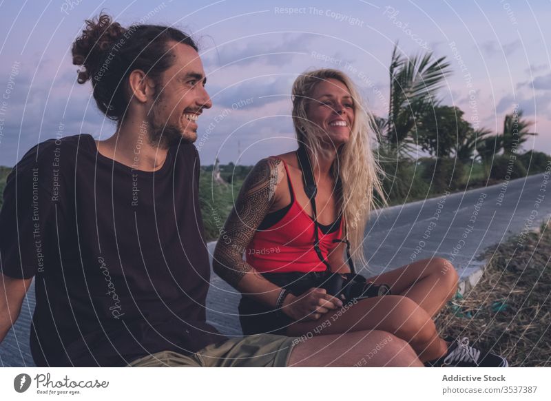 Freudiges Paar genießt Sonnenuntergang im Urlaub Abend Reisender Hipster genießen Straßenrand tropisch Freude Freiheit Inspiration Inhalt heiter Lächeln positiv