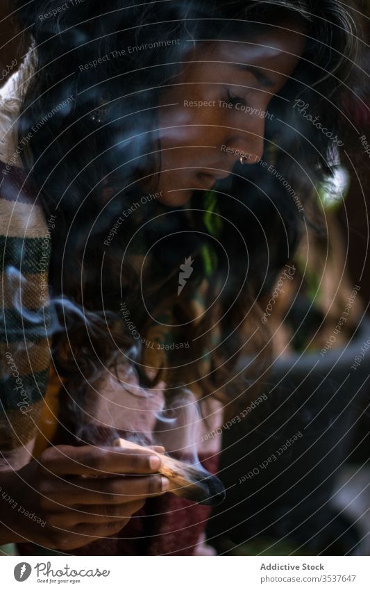 Ethnische Frau meditiert mit rauchendem Salbei-Räucherstäbchen Ritual Sprit meditieren Weihrauch Rauch ethnisch Konzentration Windstille Festakt Tradition